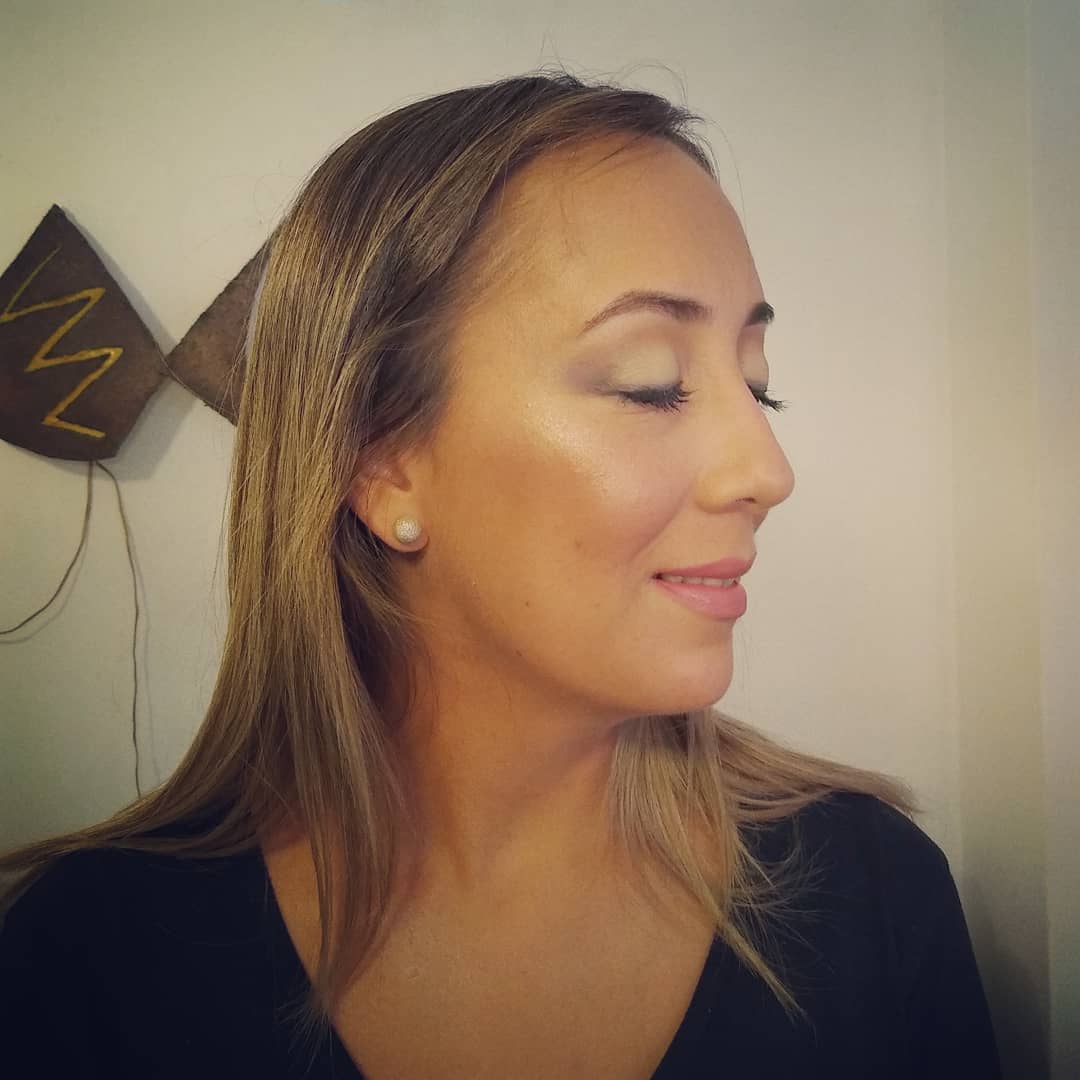 Una clienta de perfil, con los ojos cerrados, con maquillaje social luminoso y el pelo suelto